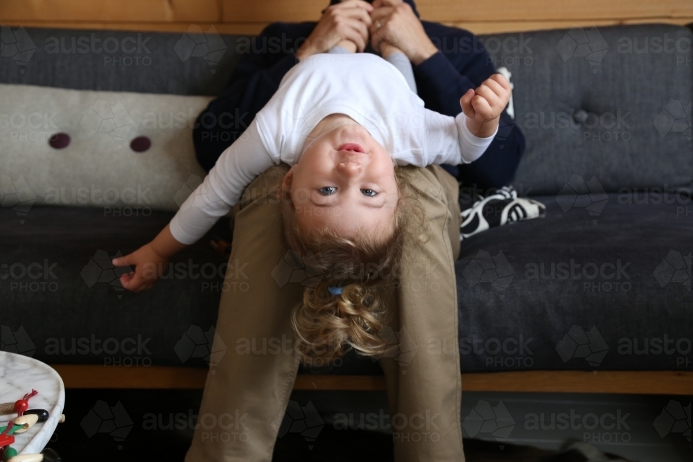 Dad with daughter upside down on couch - Australian Stock Image