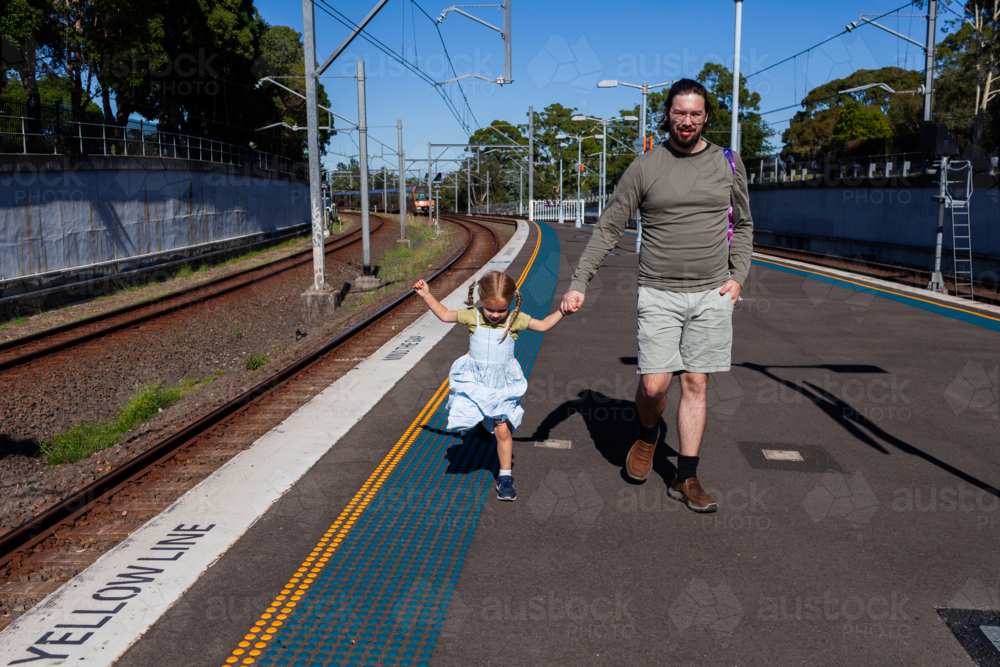 dad with little girl daughter holding hands walking together at station in Sydney suburb - Australian Stock Image