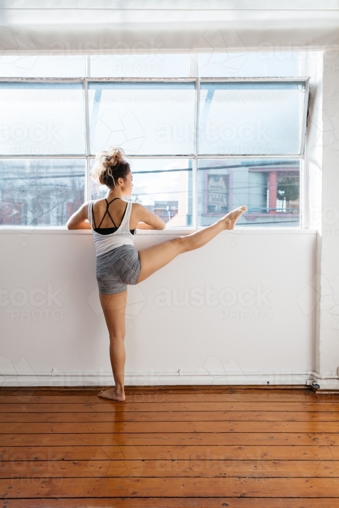 Dance instructor stretching before taking a class - Australian Stock Image