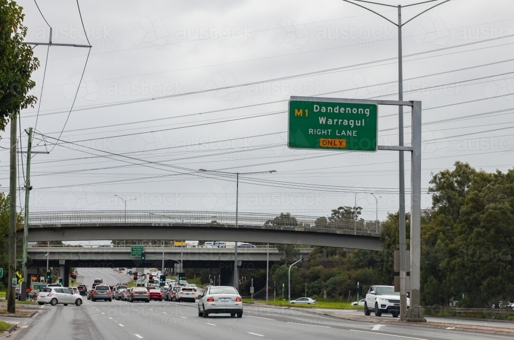 Dandenong Warragul right lane only sign above busy road with overpass and traffic lights - Australian Stock Image