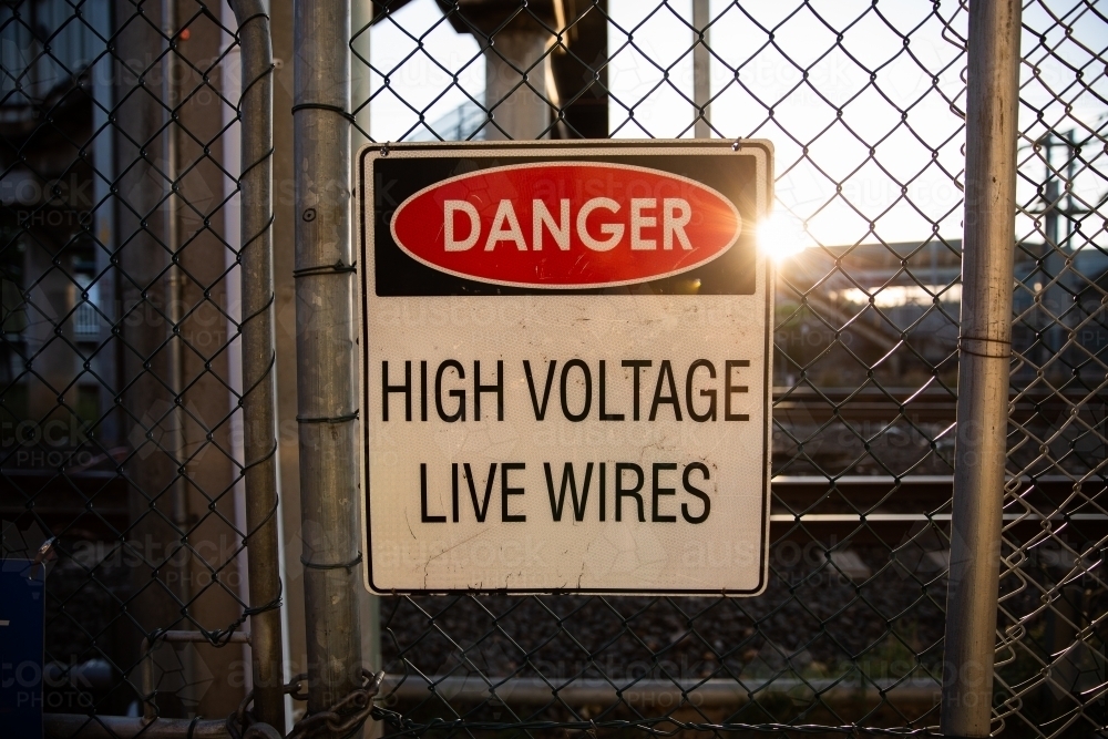 danger high voltage live wires sign on a chain link fence - Australian Stock Image