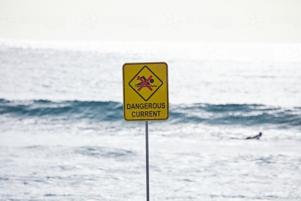 Dangerous current sign with surfer at beach - Australian Stock Image