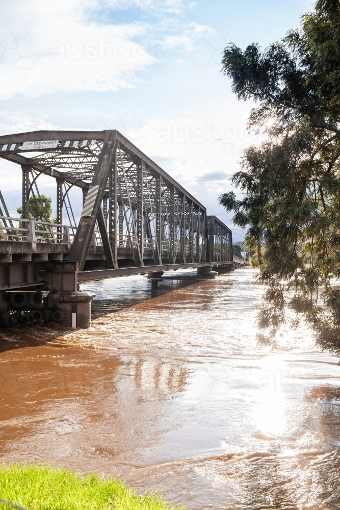 Image of Dangerous flood water rising up bridge pylons after rain