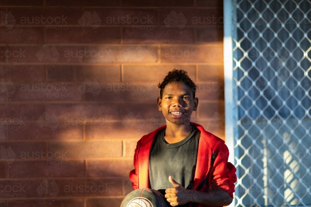 dappled light on lad near brick wall with security screen - Australian Stock Image