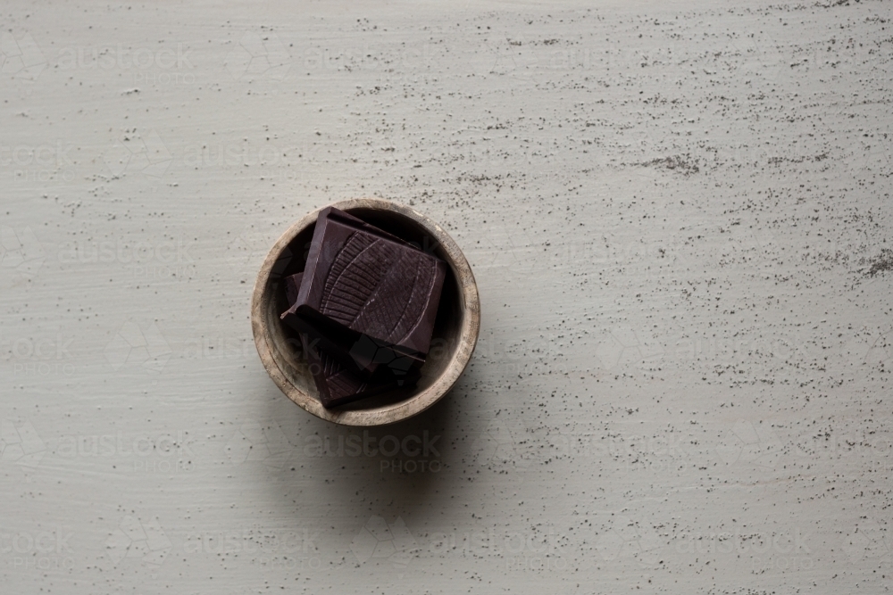 dark chocolate pieces in a small wooden bowl - Australian Stock Image