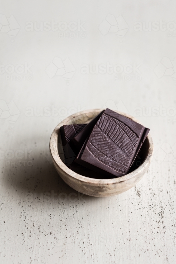 dark chocolate pieces in a small wooden bowl - Australian Stock Image