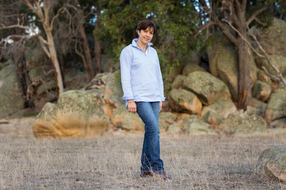 Dark haired woman in jeans standing in landscape - Australian Stock Image
