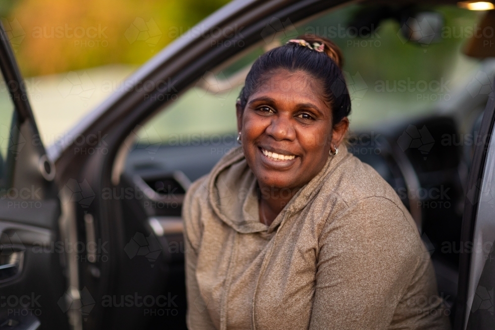 dark-skinned woman looking out of car passenger seat - Australian Stock Image