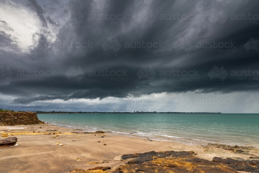 Dark storm clouds over the ocean and Darwin city - Australian Stock Image