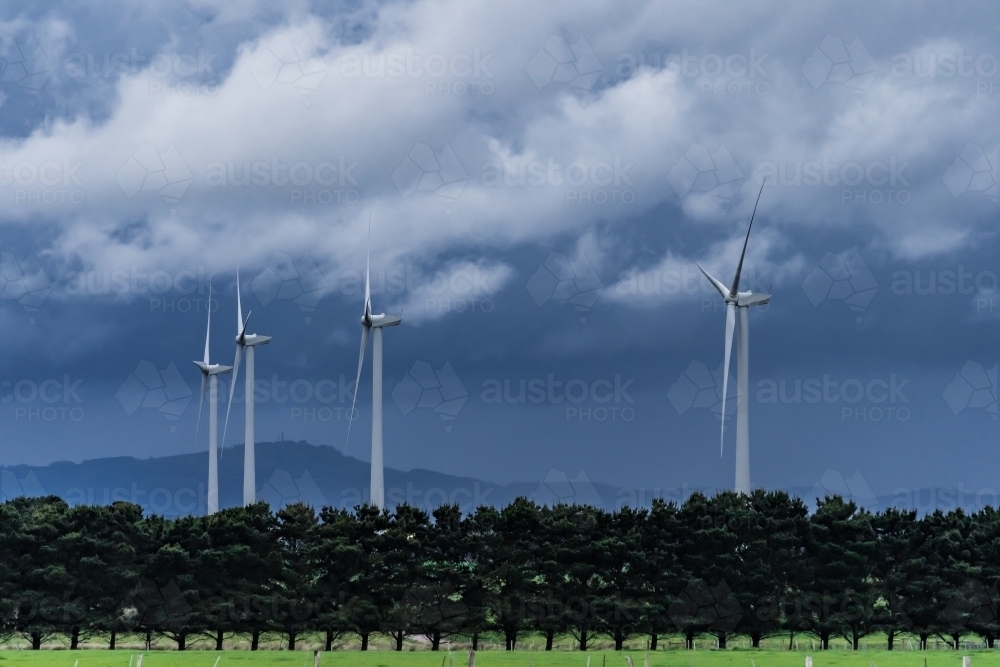 Dark stormy skies hovering over tall wind turbines - Australian Stock Image