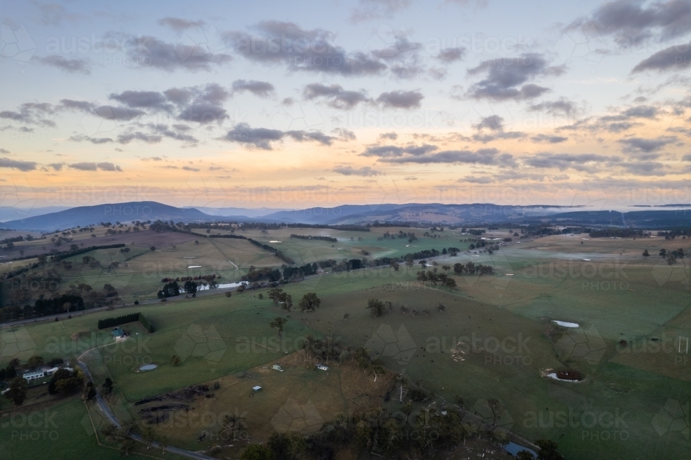 Dawn colours in the sky while the green countryside is shown below in rural Australia - Australian Stock Image