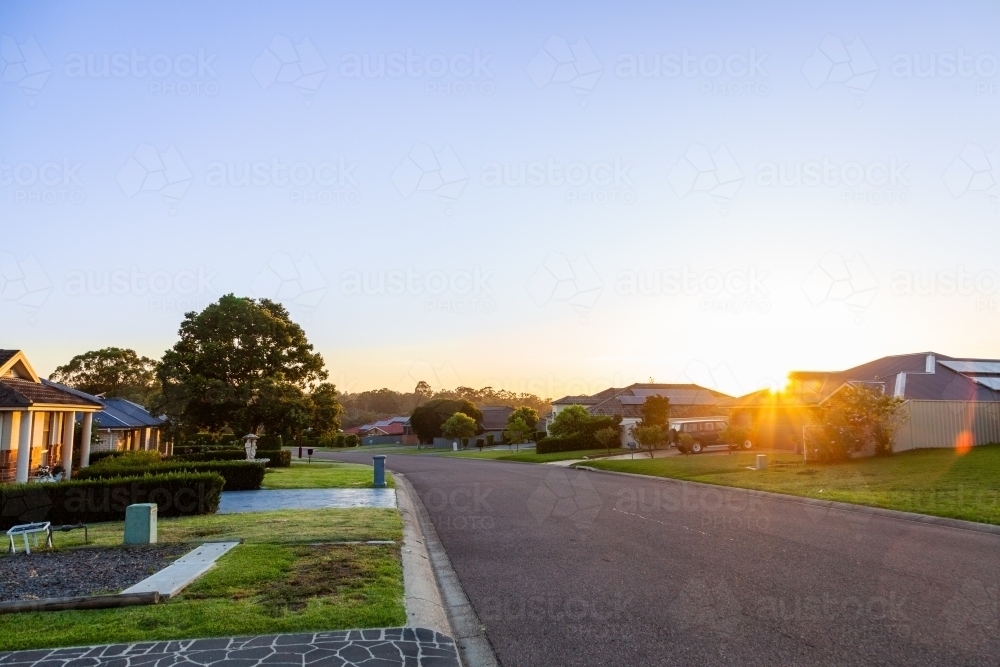 Dawn on quiet suburban street in town with big blue sky - Australian Stock Image