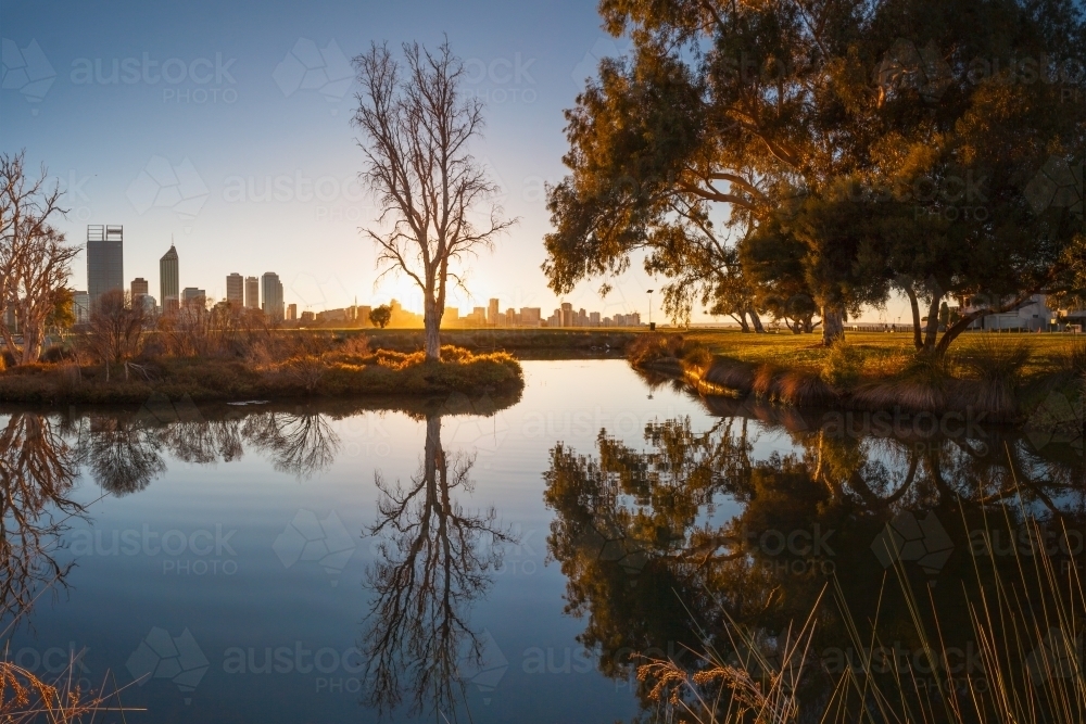 Dawn over an inner city lake with reflections of nearby trees - Australian Stock Image