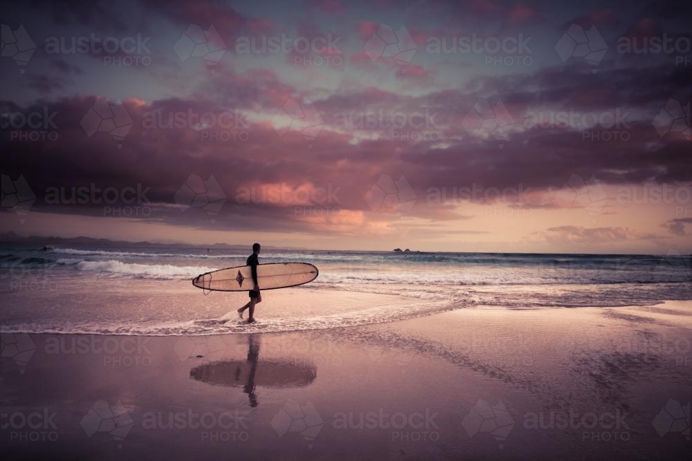 Dawn surfer at the beach in Byron Bay (high iso) - Australian Stock Image