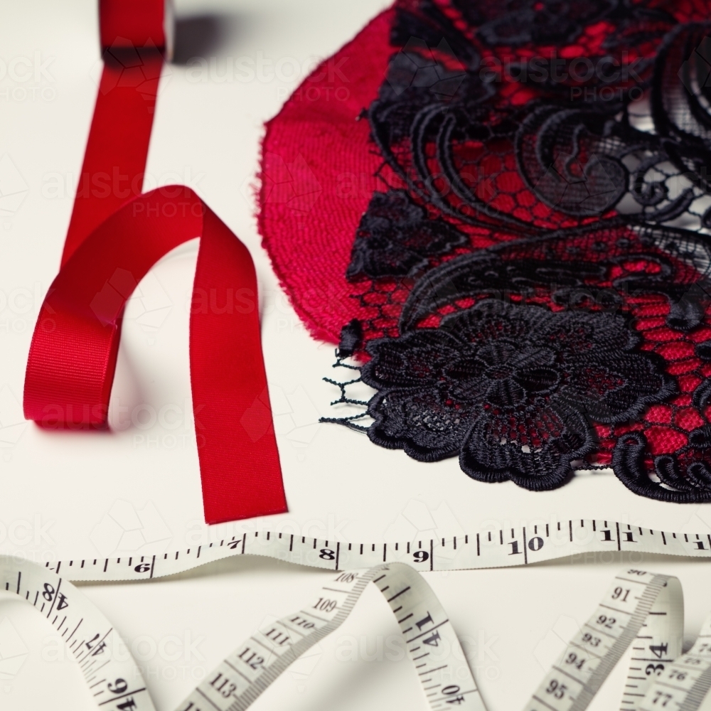 Deconstructed red and black millinery materials and tape measure - Australian Stock Image