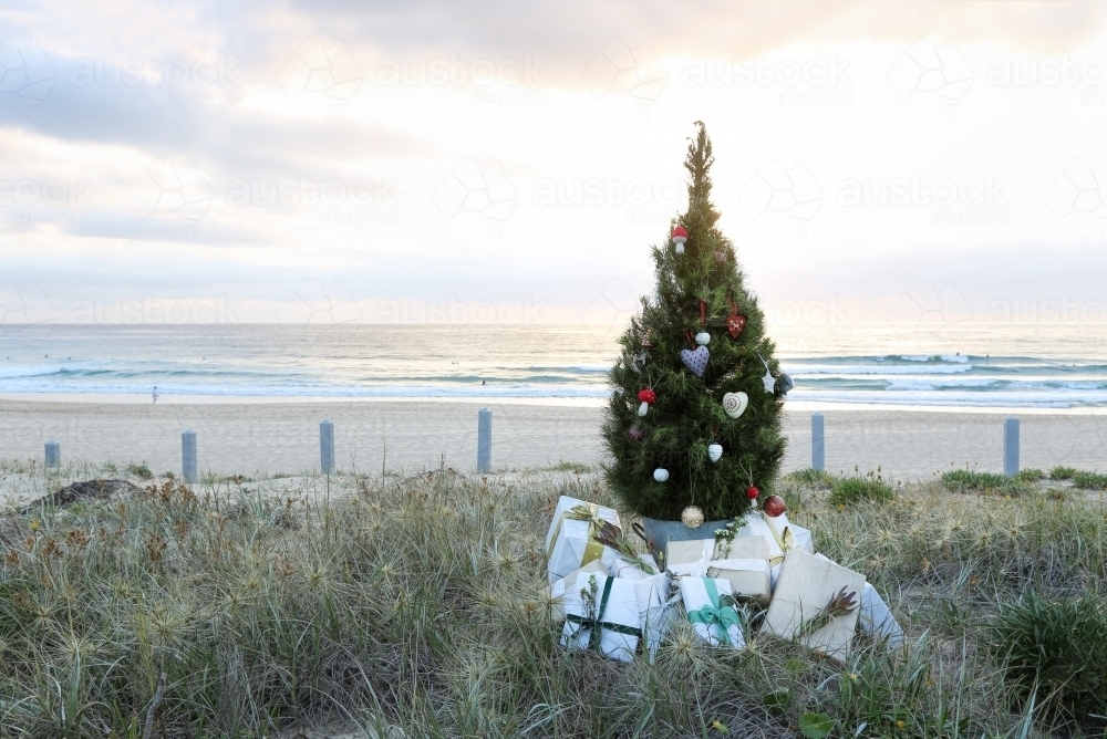 Decorated Christmas tree and presents with beach sunrise in background - Australian Stock Image