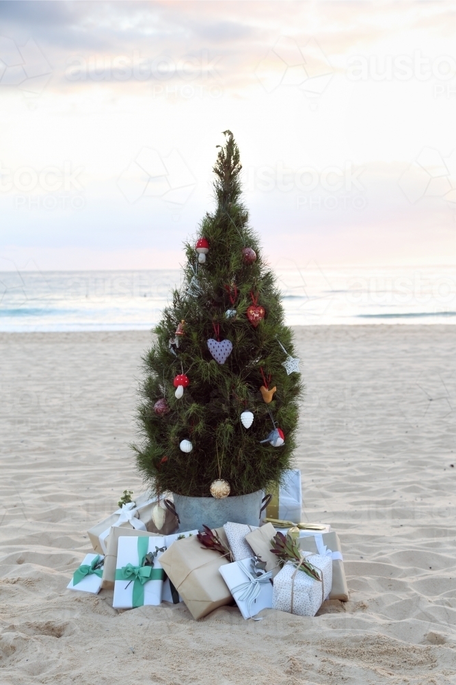 Decorated Christmas tree with presents on beach at sunrise - Australian Stock Image
