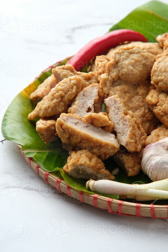 Deep fried Cha Lua slices served on a banana leaf in a woven basket. - Australian Stock Image