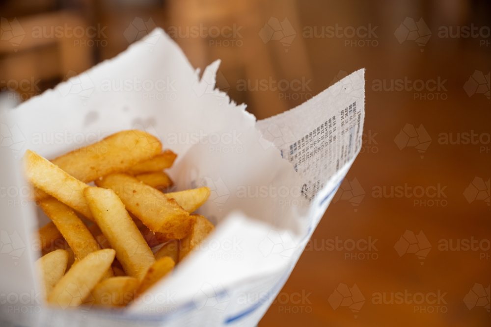 Deep fried chips in a wire basket lined with wax paper - Australian Stock Image