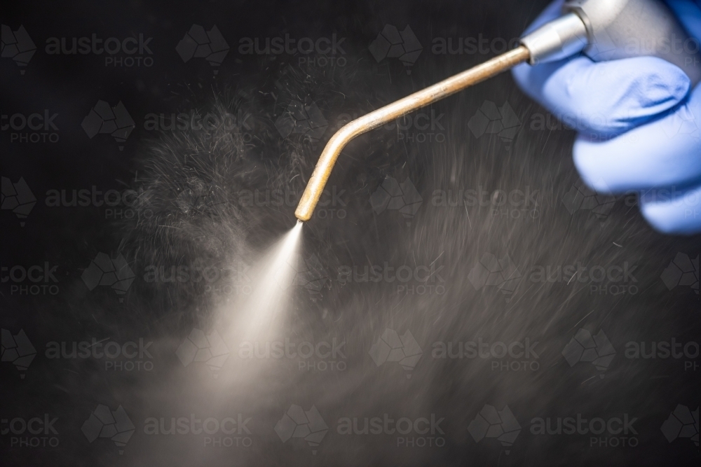 Dental air water syringe with water spray on black background - Australian Stock Image