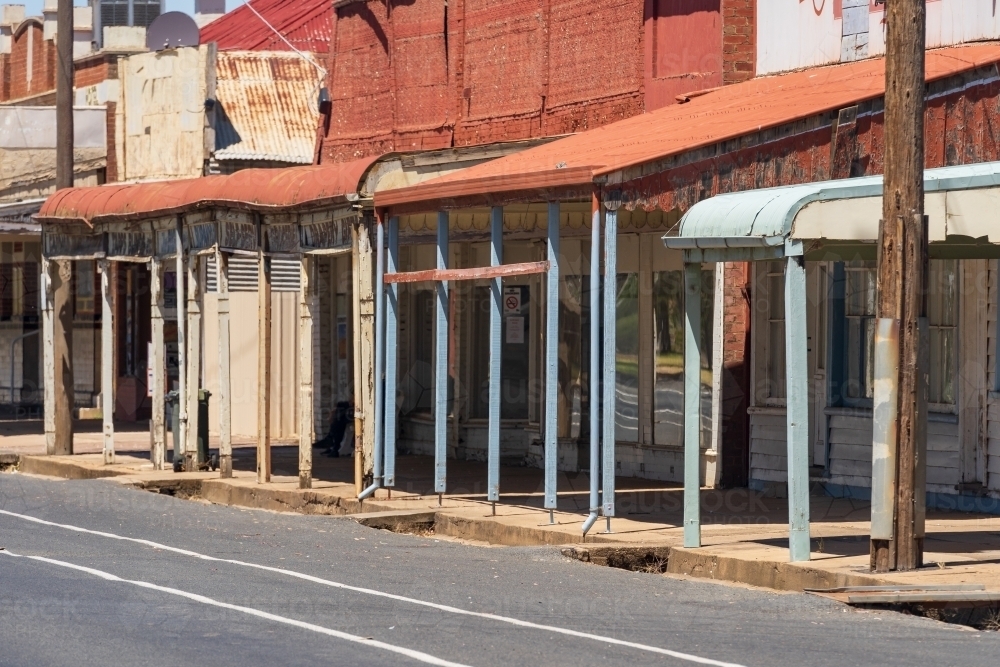 Image of Deserted shops and verandas along the roadside of a small ...