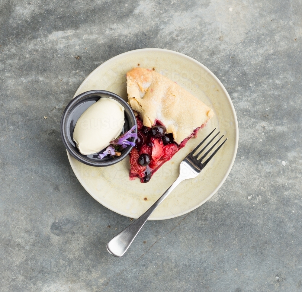 Dessert of strawberry and blueberry tart with cream on a concrete table - Australian Stock Image