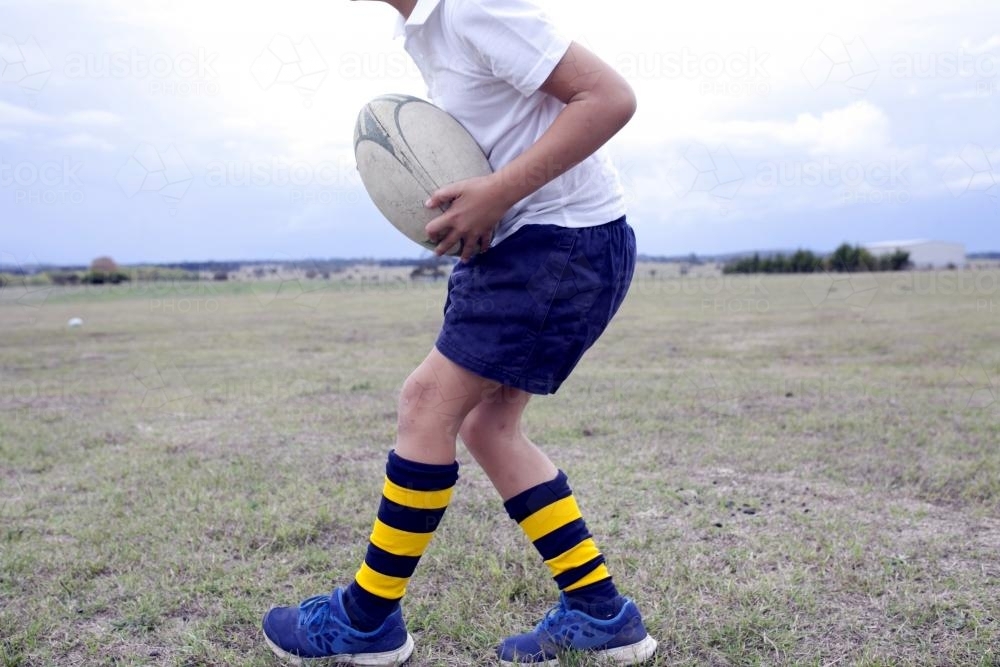 Detail of a boy catching a football in a field - Australian Stock Image