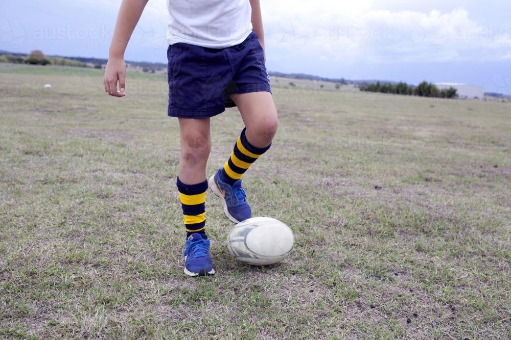 Detail of a boy playing with a football on the ground - Australian Stock Image