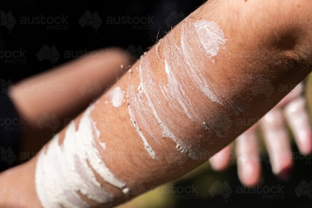 Detail of Aboriginal person applying ochre paint to skin before ceremony - Australian Stock Image