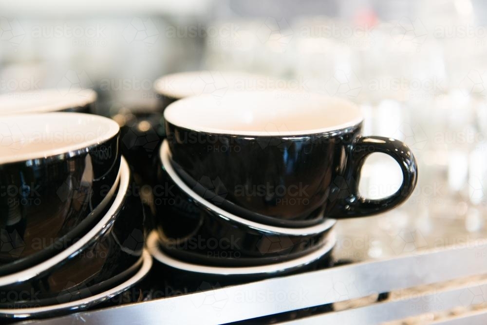 Detail of black coffee cups and glasses stacked in a cafe - Australian Stock Image