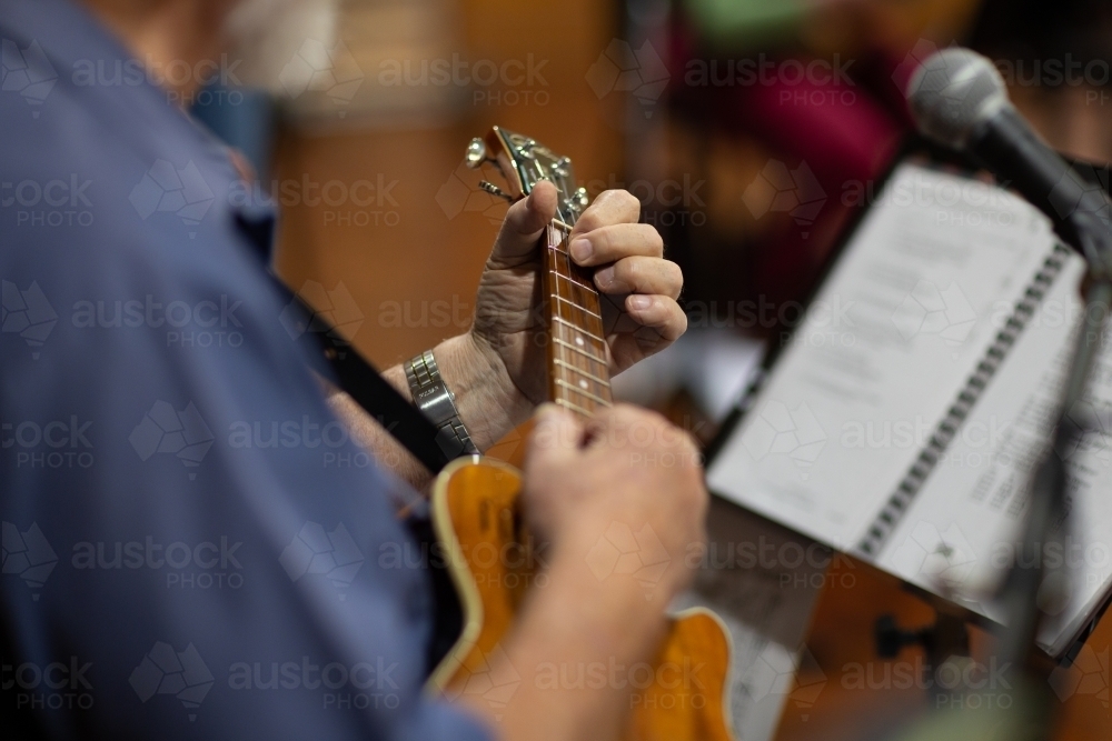 detail of man reading music and playing ukulele - Australian Stock Image