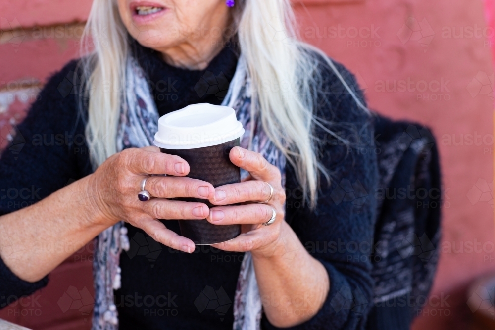 detail of older lady holding takeaway cup with two hands - Australian Stock Image