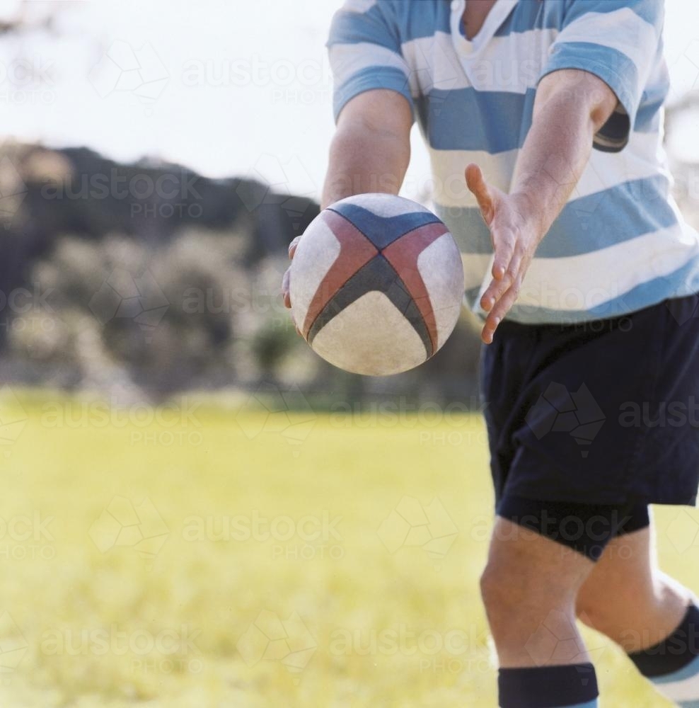 Detail of person passing a rugby union ball - Australian Stock Image