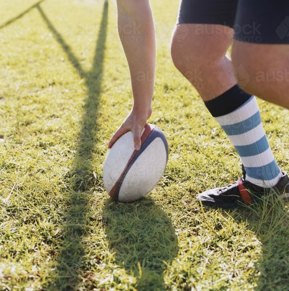 Detail of person placing a rugby union ball on the ground - Australian Stock Image