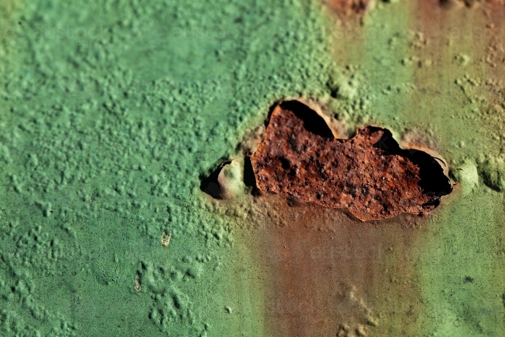 Detail of rusted holes in painted metal surface - Australian Stock Image