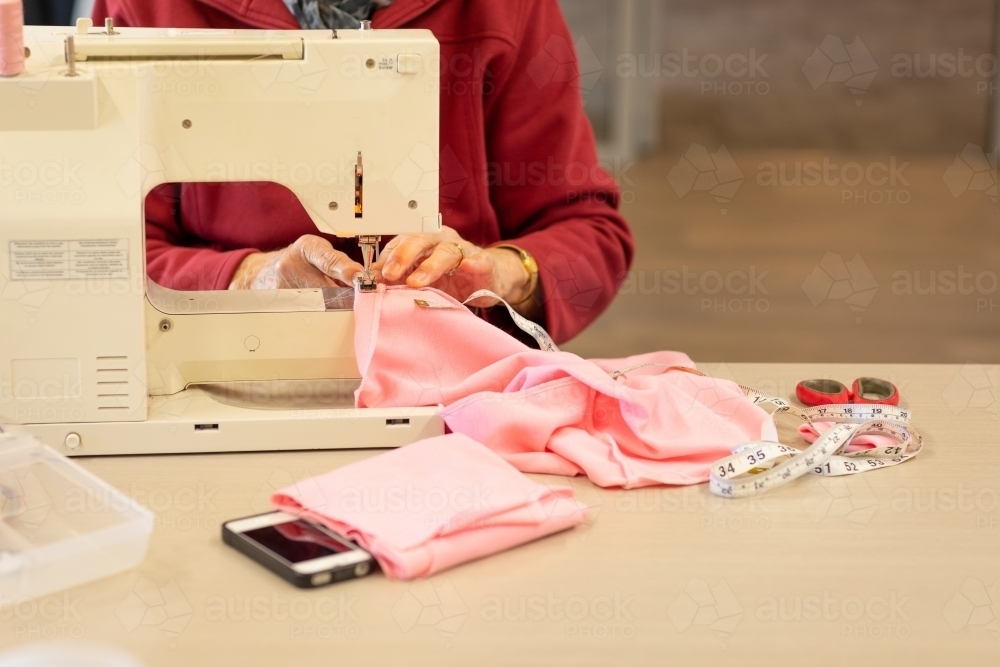 detail of sewing machine and fabric with lady stitching - Australian Stock Image