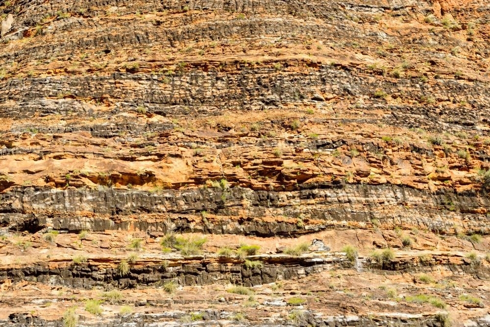 Detail shot of heavily textured and layered rock with yellow and orange colours - Australian Stock Image