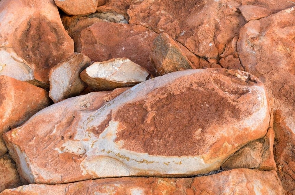 Detail shot of heavily textured pink, red and orange rock cracks and crevices - Australian Stock Image