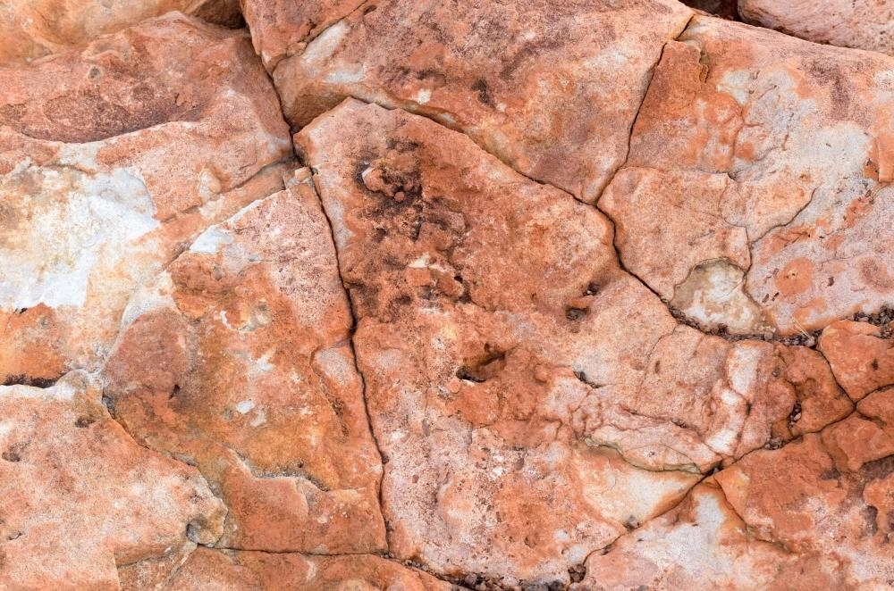 Detail shot of heavily textured pink, red and orange rock cracks and crevices - Australian Stock Image