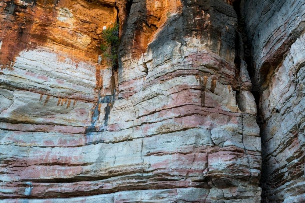 Detail shot of layered and patterned rock with orange, pink and yellow colours - Australian Stock Image