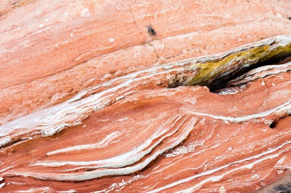 Detail shot of layered and patterned rock with orange, pink and yellow colours - Australian Stock Image