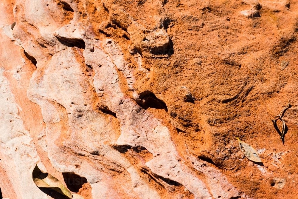 Detail shot of layered and patterned rock with orange, pink and yellow colours - Australian Stock Image