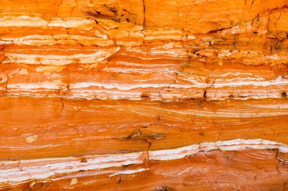 Detail shot of layered and patterned rock with orange, pink and yellow colours - Australian Stock Image