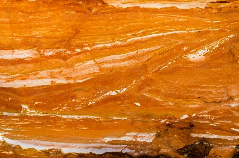 Detail shot of layered and patterned rock with orange, pink and yellow colours - Australian Stock Image
