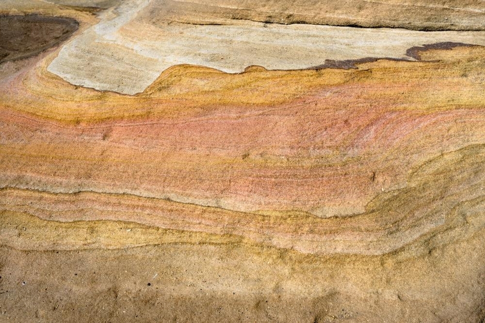 Detail shot of layered pink, yellow and orange sedimentary rock - Australian Stock Image