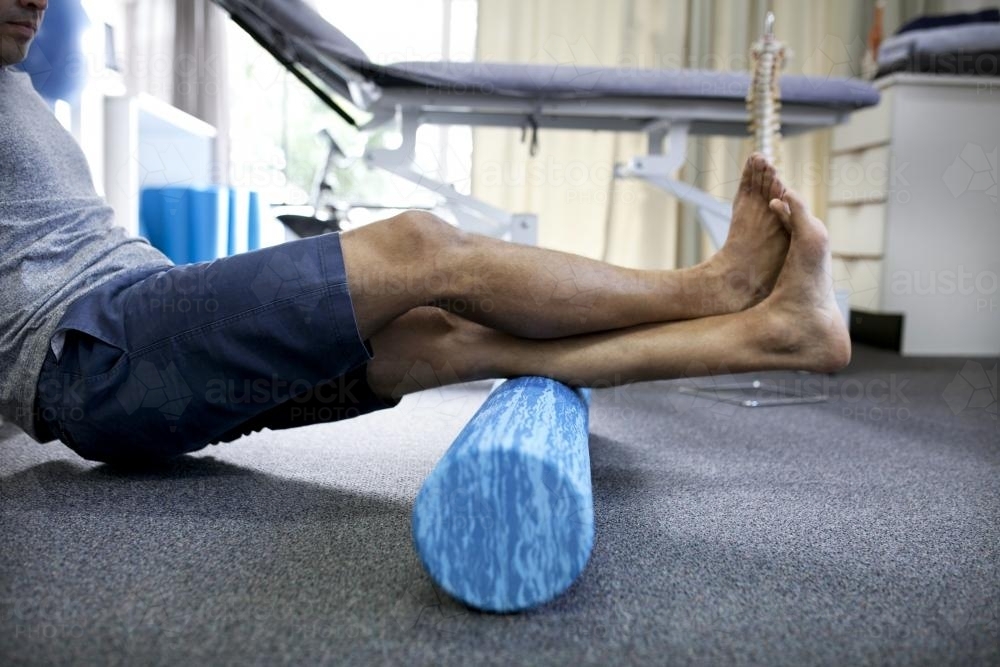 Detail shot of male patient using a foam roller in a physio studio - Australian Stock Image