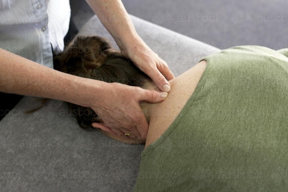 Detail shot of physiotherapist treating a patient's neck - Australian Stock Image