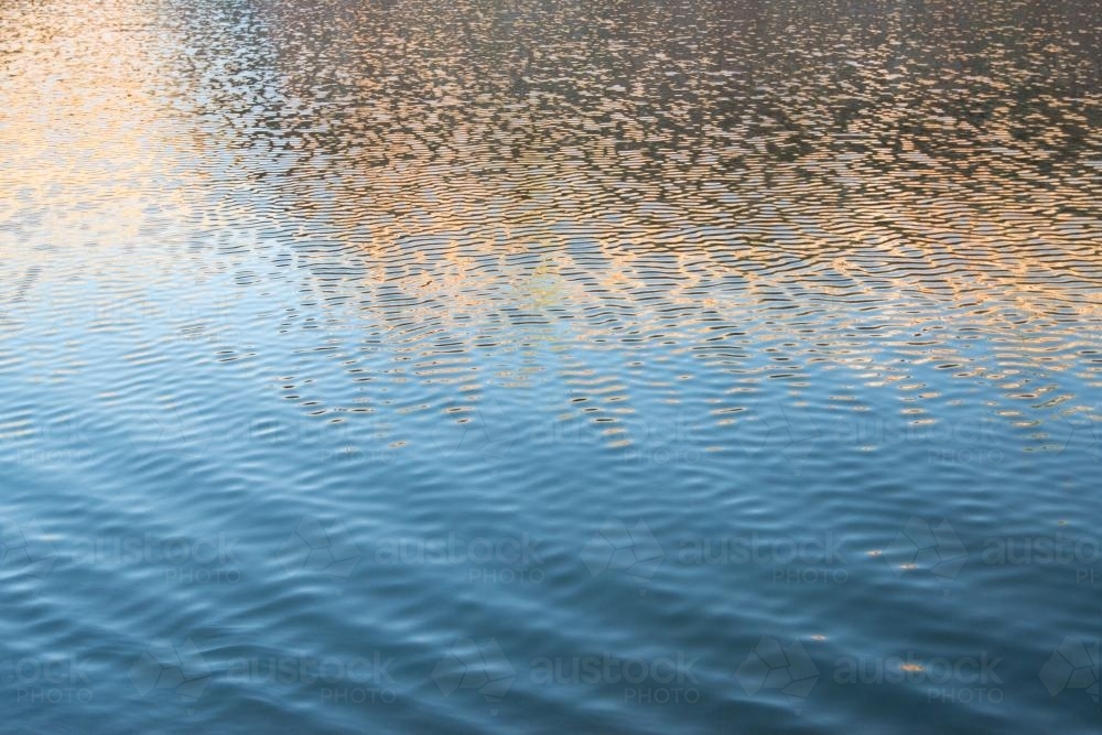 Detail shot of water with ripples and blue and orange tones - Australian Stock Image