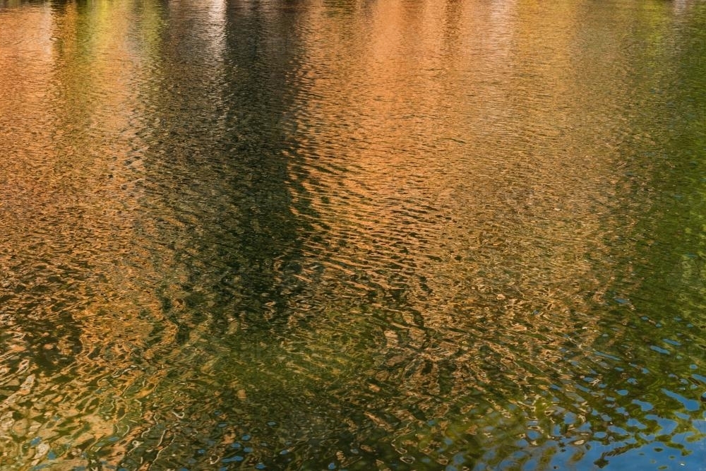 Detail shot of water with ripples and green and orange tones - Australian Stock Image
