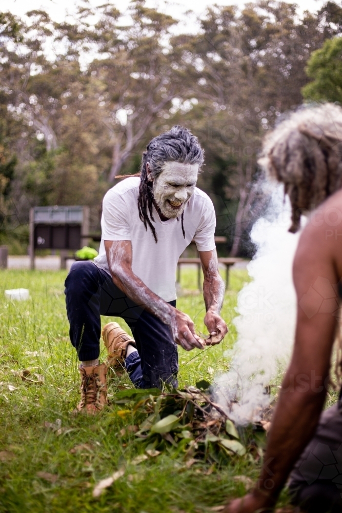 dharawal man adding leaves to a bundle for a smoking ceremony - Australian Stock Image